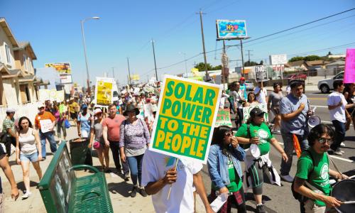 一群人举着“太阳能给人民”的标语游行."