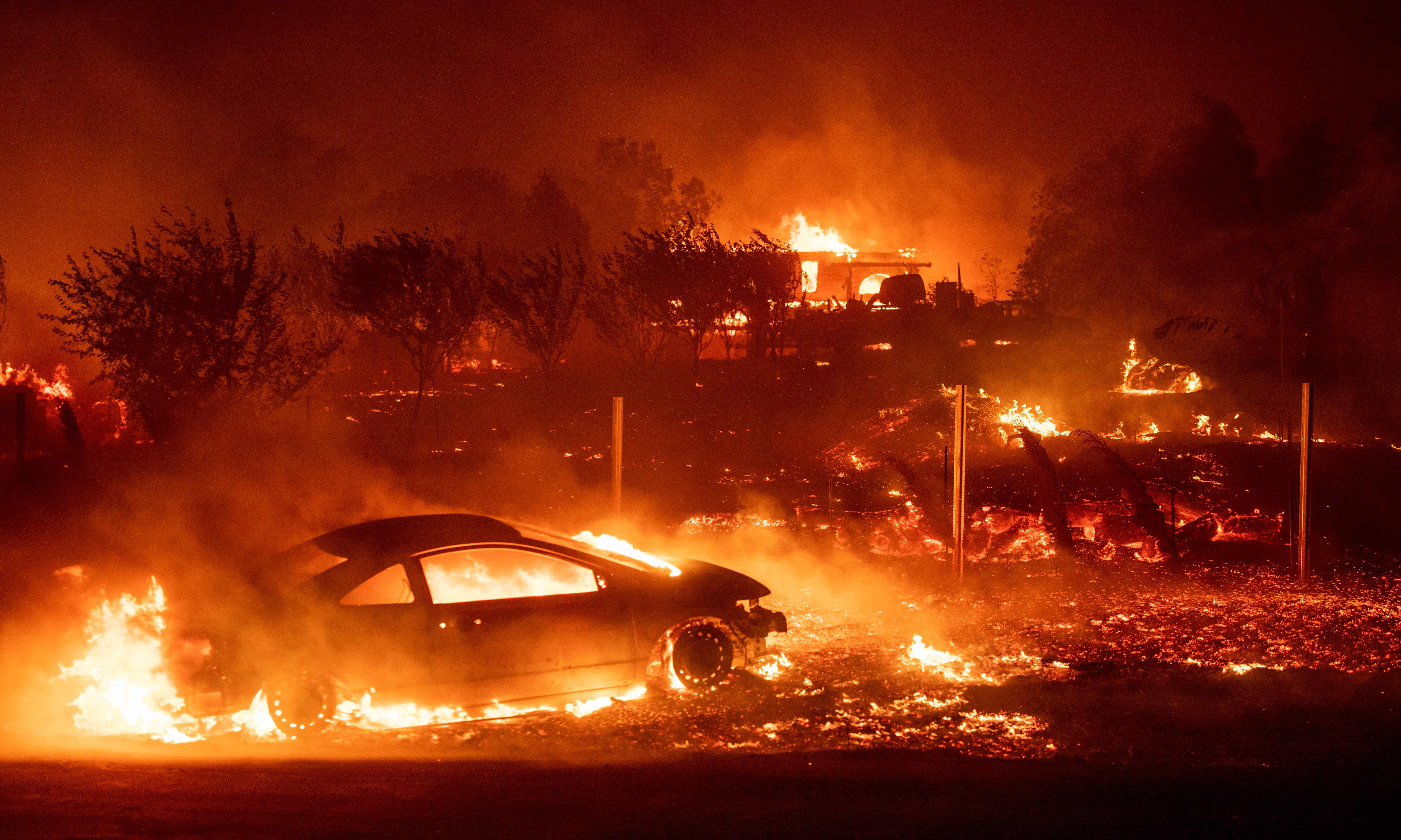 A car and a home burning in a wildfire