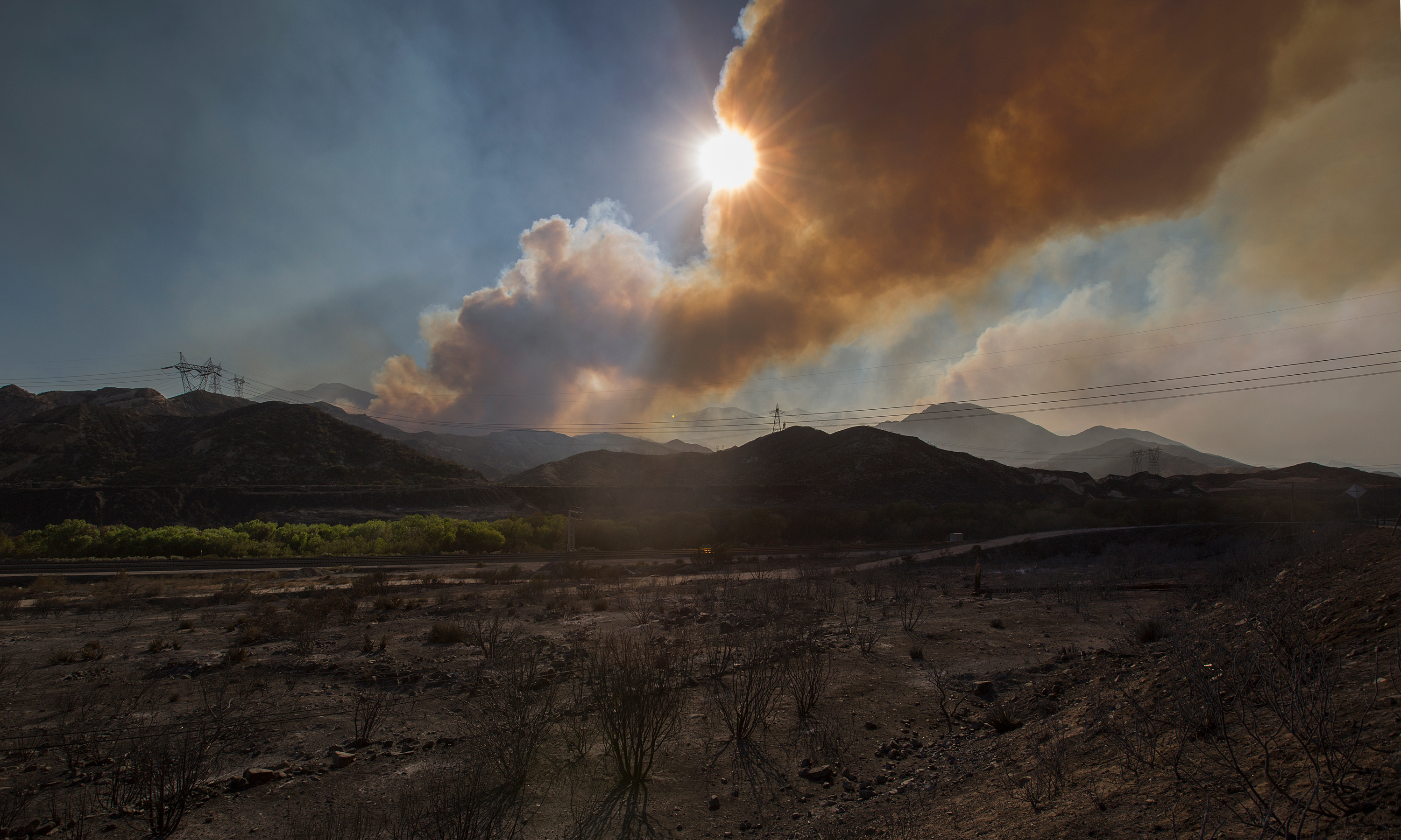 A wildfire smoke plume obscures the sun