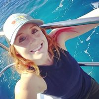 Jess Phoenix is on a boat in clear blue water, wearing a baseball hat