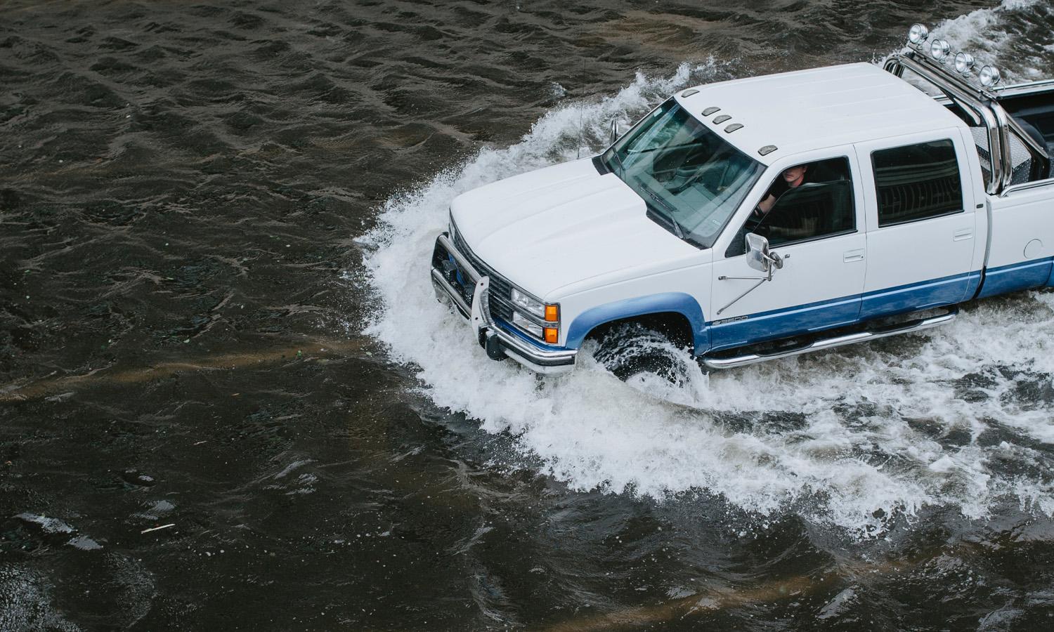 A truck drives through flooded water.