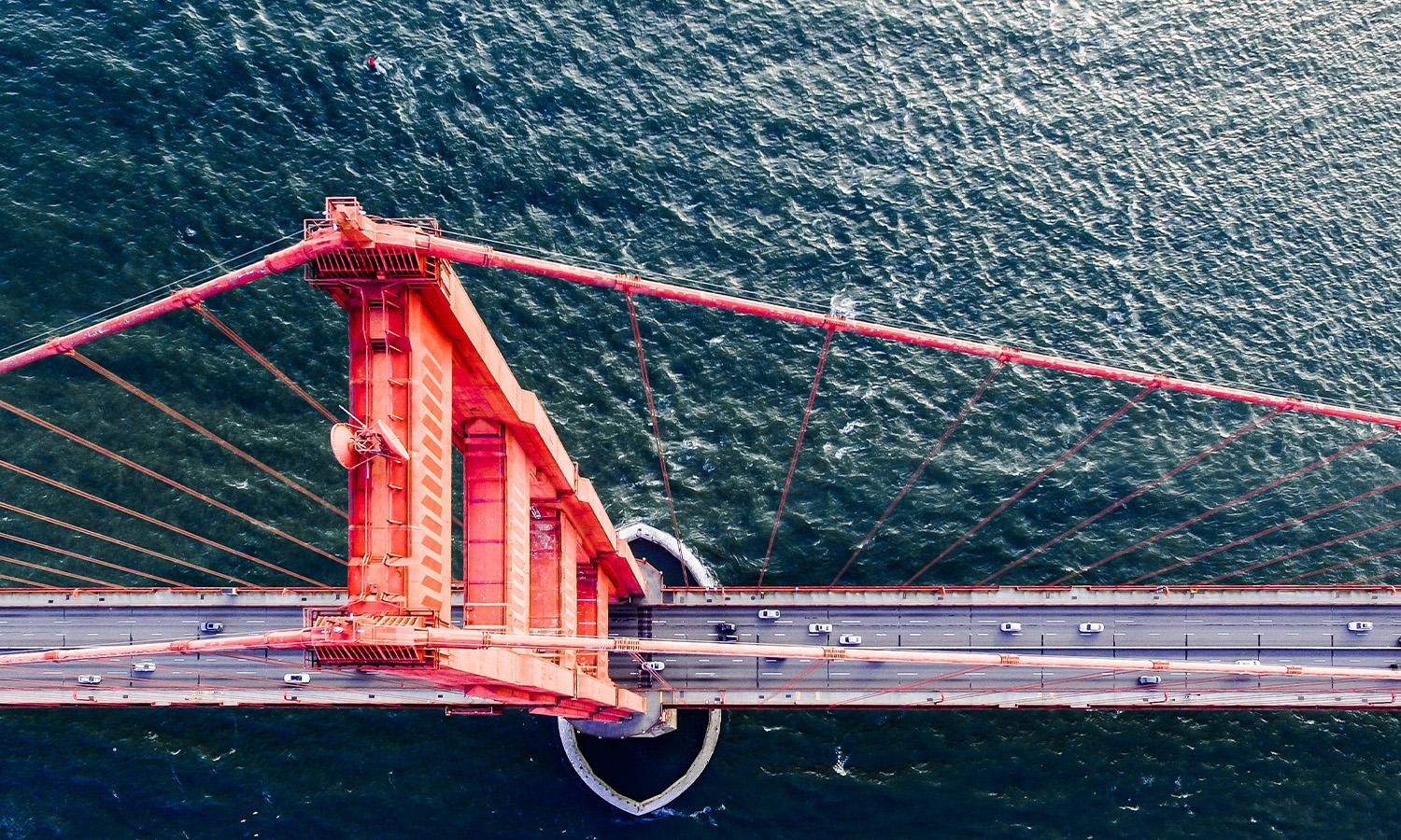 An aerial view of cars driving over the Golden Gate bridge. 