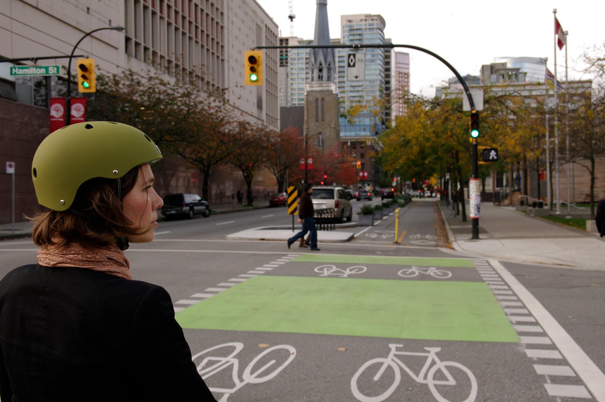 Woman facing a separated bicycle lane on Dunsmuir Street, downtown Vancouver, Canada