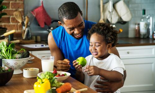 Father holding child about to eat an apple