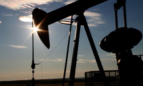 An oil well silhouetted against a setting sun