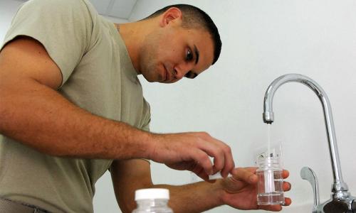 Airman pouring water into bottle for testing