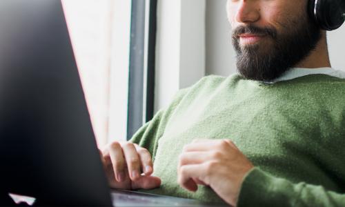 Person wearing headphones sitting in front of a laptop.