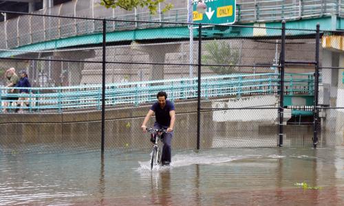 Person biking through flooded street.