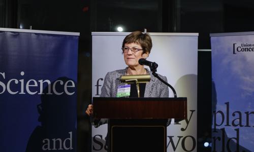 A woman speaking in front a sign that says science