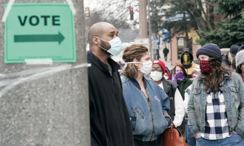 people in masks waiting to vote