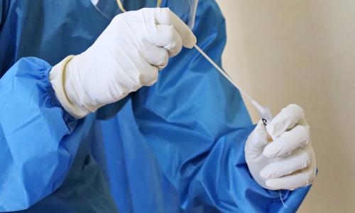 A gloved doctor holds a swab test.