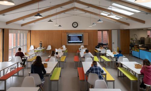 School children sit at individual, spaced out, lunch tables.