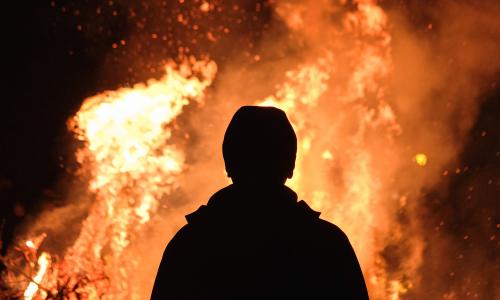 A person standing in front of a fire