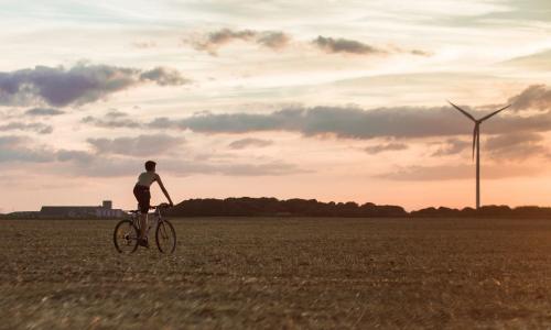 Man riding bike near wind turbine