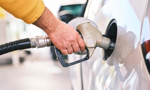 A person pumps gas into tank of white car