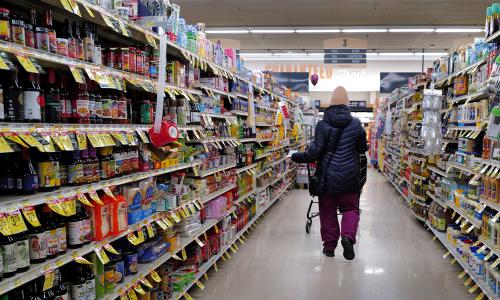 A person walks down the aisle of a grocery store.