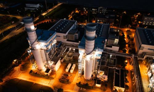 Two smokestacks at night. 