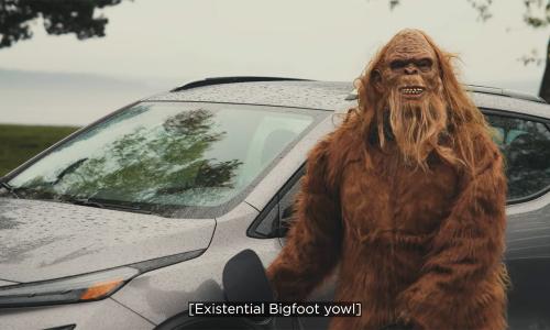 A still from the video Ensuring a Green Future with Responsible Practices where bigfoot stands in front of an electric vehicle.