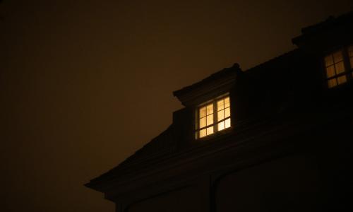 A home at night with an illuminated window.