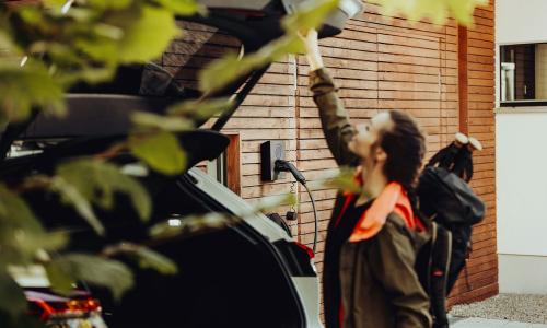 woman closing ev trunk with charger in background