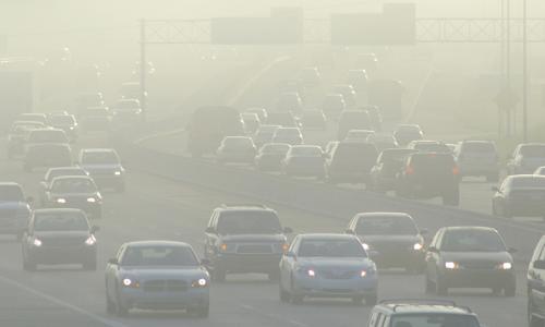 Cars in a haze on a highway.